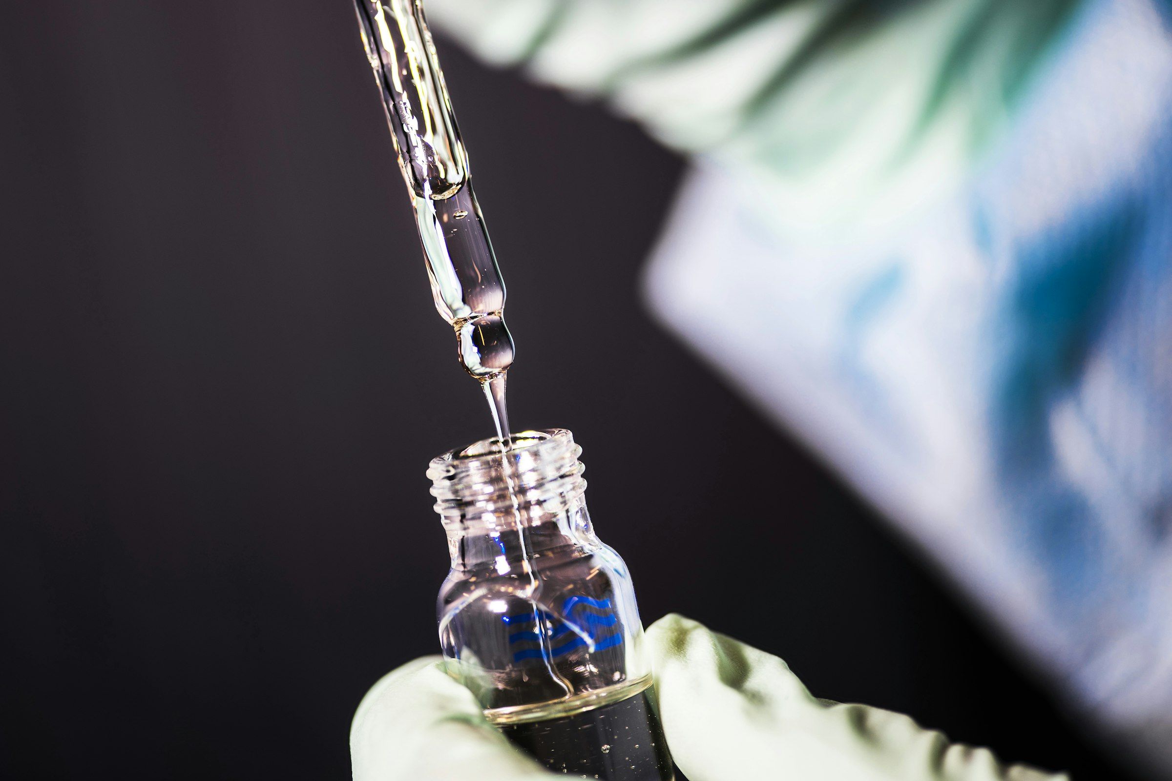 Dropper releasing liquid into a glass vial